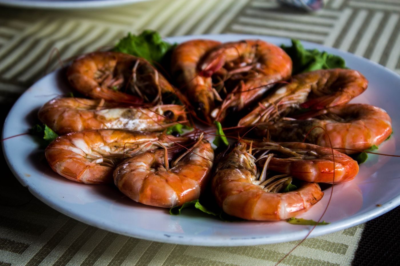 Camarones asados servidos en un plato blanco con lechuga