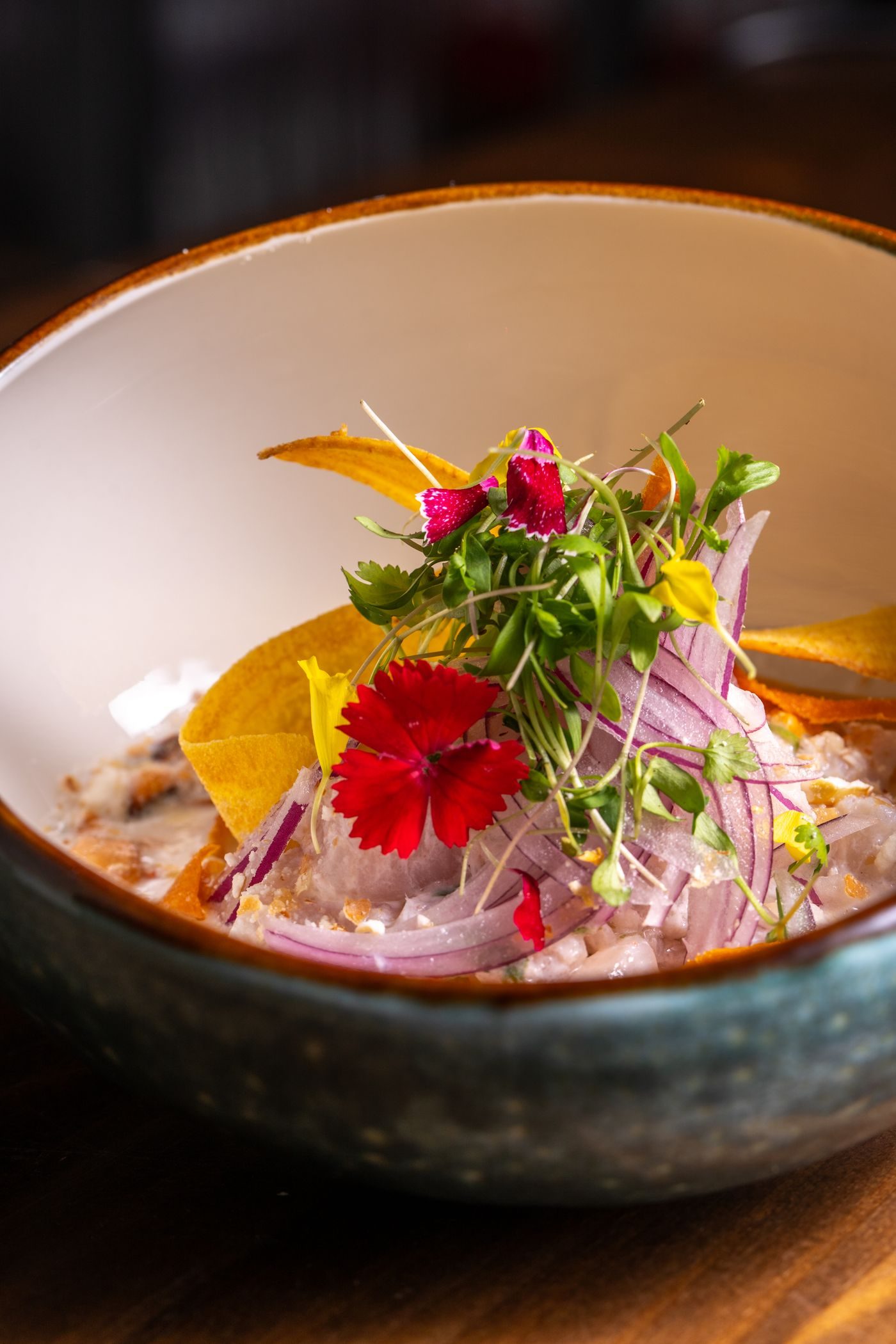 Ceviche fresco con cebolla morada y flores comestibles en plato de cerámica